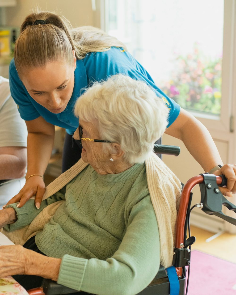 A caregiver helping an older woman with an activity at a table